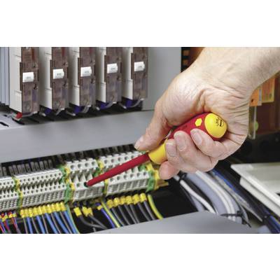 Een hand houdt een schroevendraaier vast en werkt aan een open elektrische schakelkast, omringd door kabels en aansluitingen.