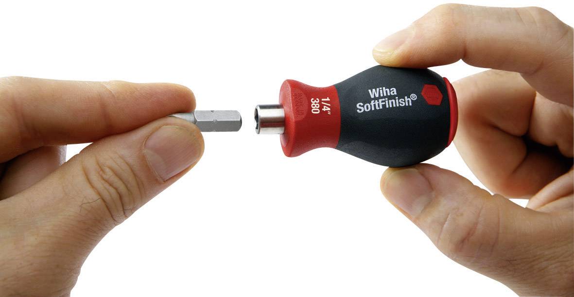 Een hand houdt een schroevendraaiergreep vast, terwijl de andere hand een bit plaatst. De greep is voorzien van de tekst 'Wiha SoftFinish'.