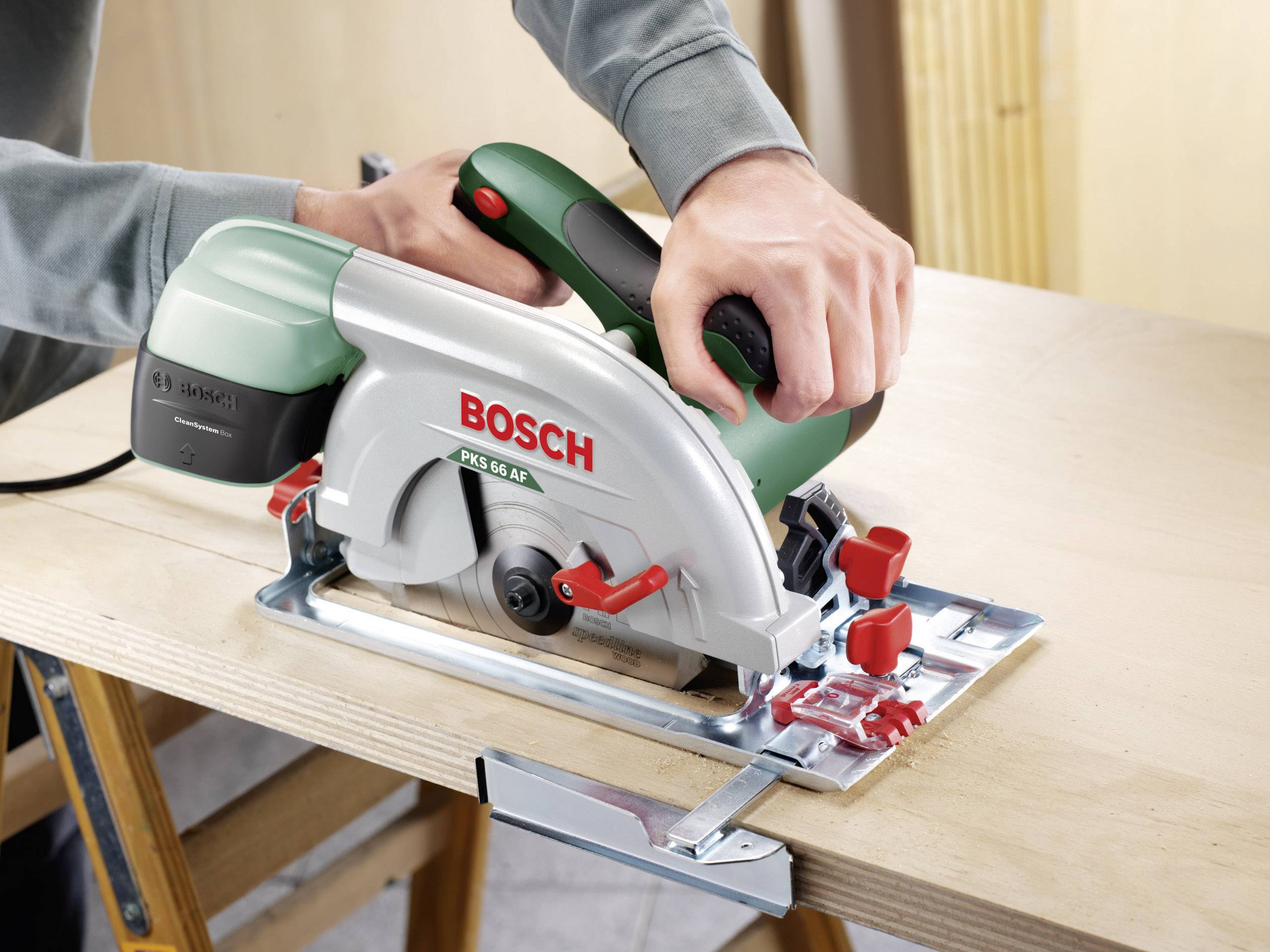 Een persoon zaagt met een Bosch-handcirkelzaag een houten plank op een werkbank.