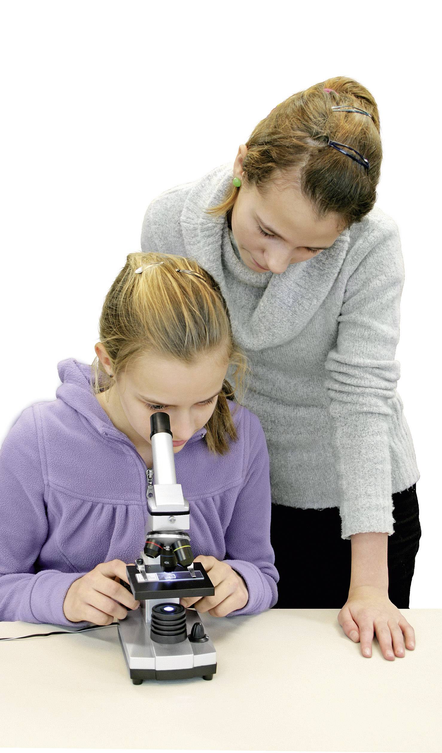 Twee meisjes bestuderen een object door een microscoop. Eén kijkt door de lens, terwijl de andere over haar schouder meekijkt.