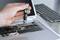 Een hand repareert een opengevouwen laptop met een schroevendraaier. De binnenkant van de laptop is zichtbaar. Op de achtergrond ligt een toetsenbord.