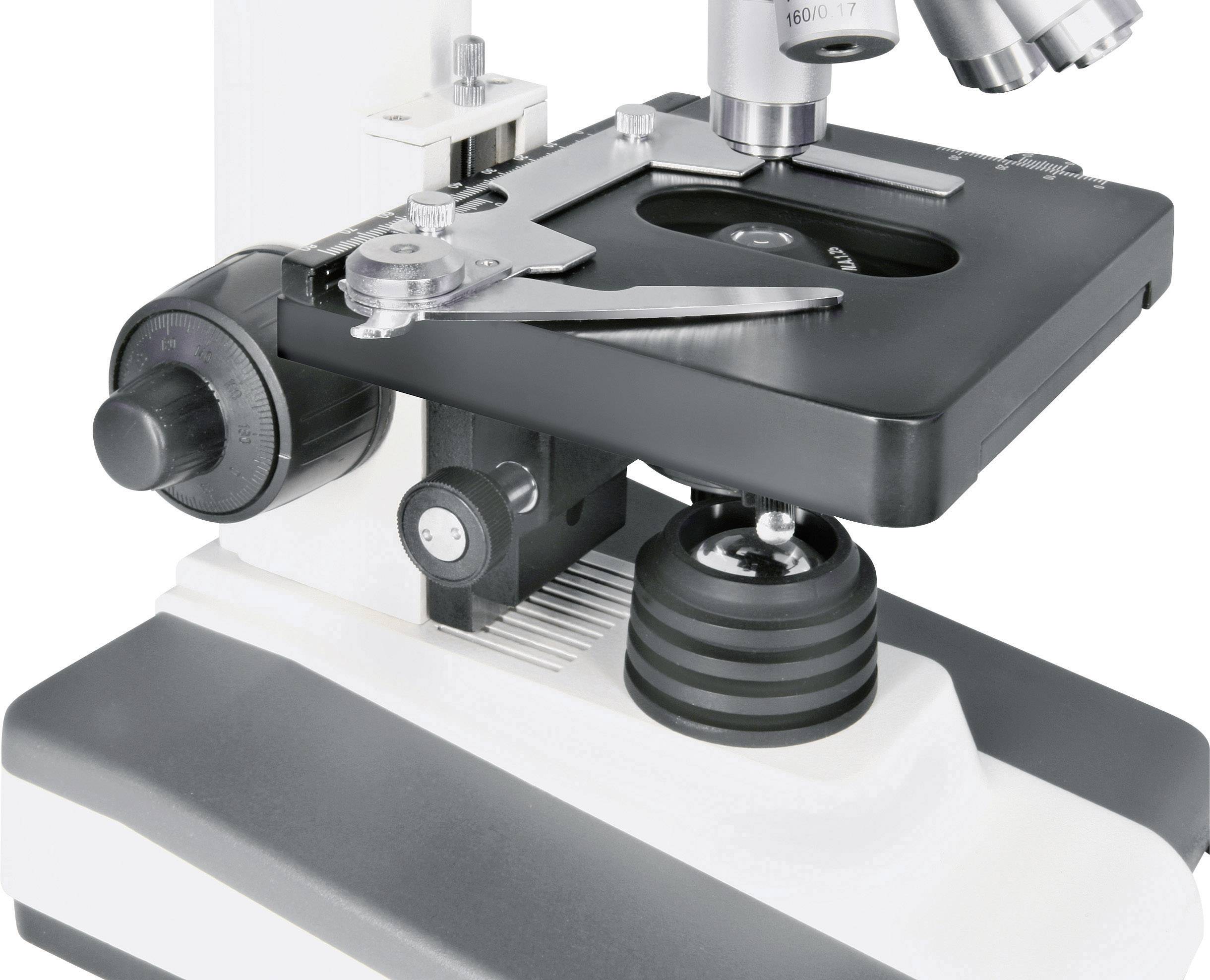 Een close-up van een microscoop met scherpstelwiel en objectrevolver, staand op een tafel.