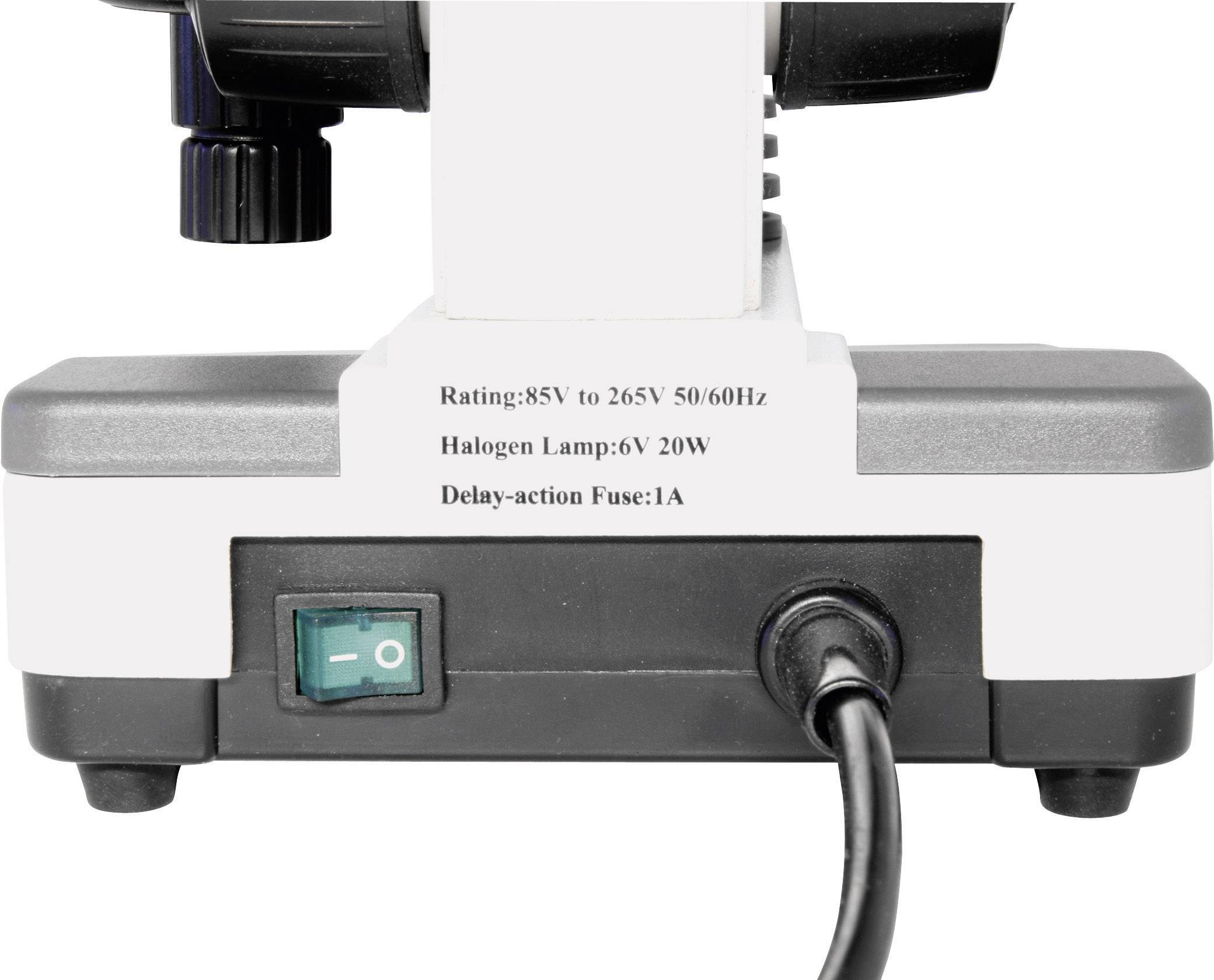 De achterkant van een microscoop toont technische specificaties: 'Spanning: 85V tot 265V, Halogeenlamp: 6V 20W, Zekering: 1A'.