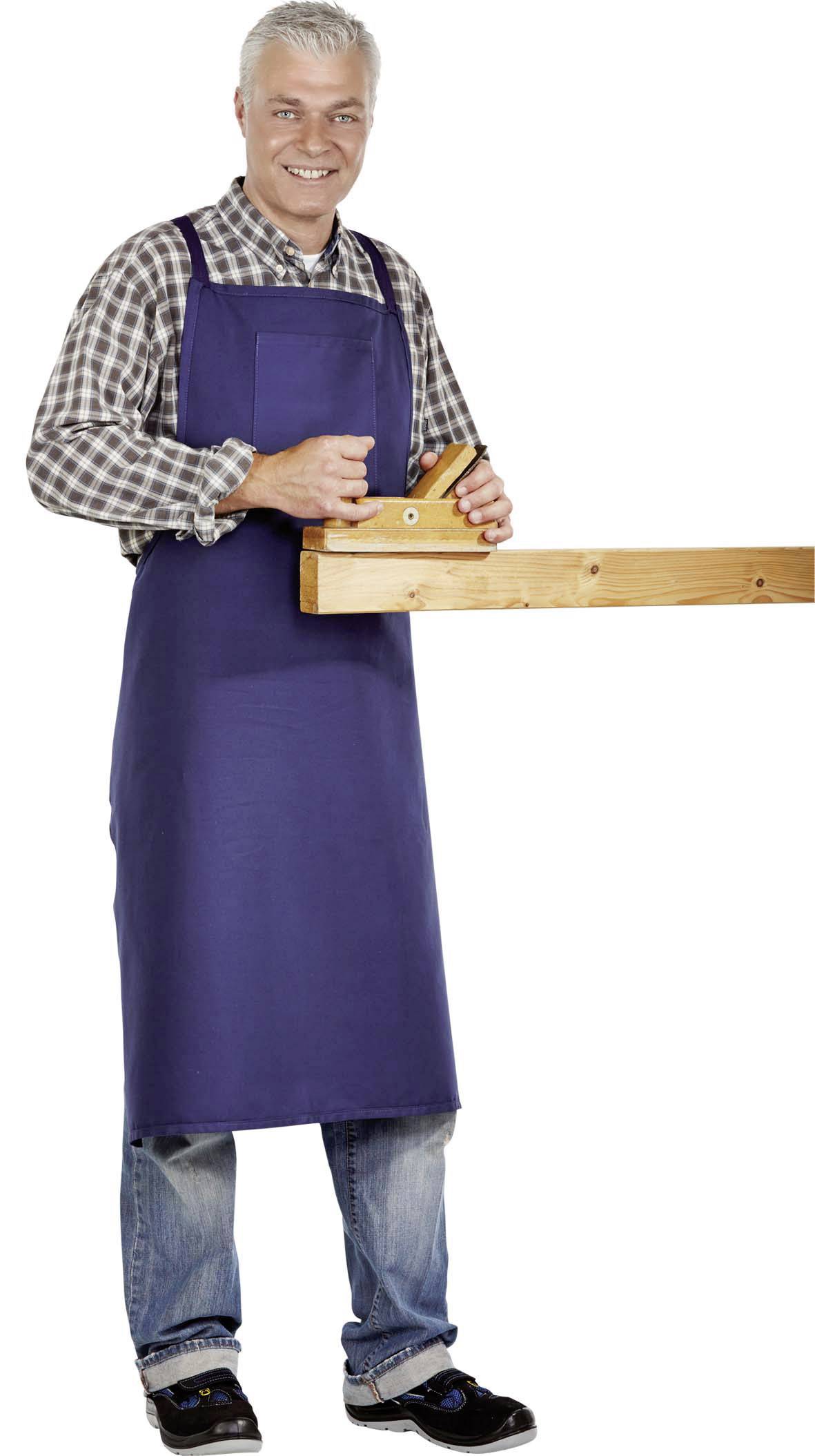 Een man staat en houdt een houten plank vast met een gereedschap. Hij draagt een blauwe schort en glimlacht naar de camera.