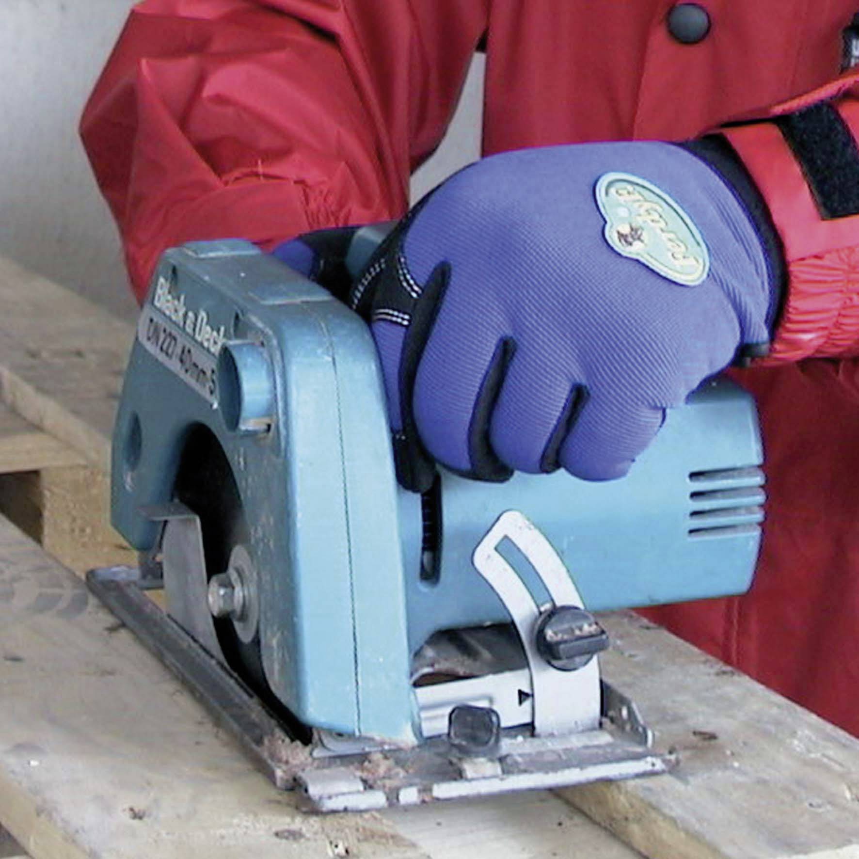 Een persoon met blauwe handschoenen gebruikt een cirkelzaag om een houten plank door te zagen op een werkbank.