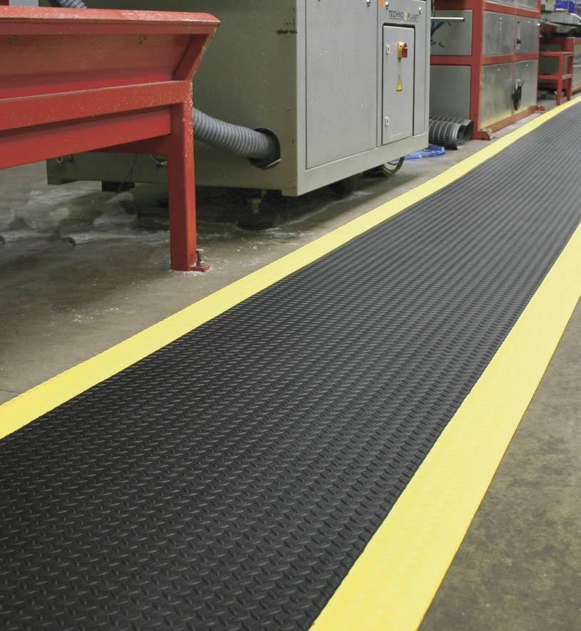 Veiligheidsmat met gele strepen ligt in een industriële omgeving voor machines om de stroefheid en veiligheid te verhogen.