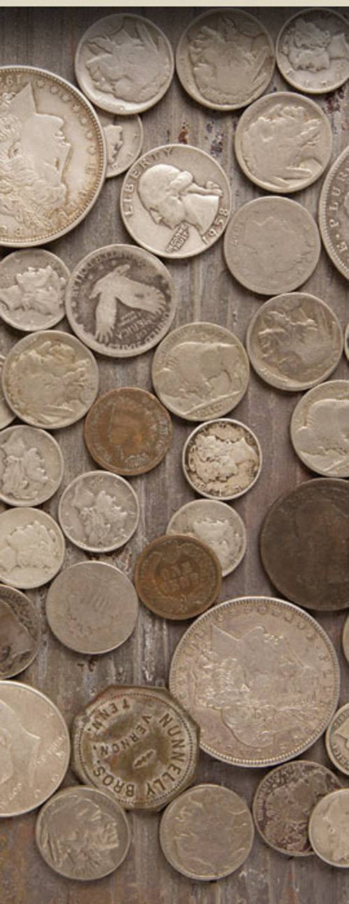 Een verzameling oude munten van verschillende grootten en kleuren ligt onregelmatig verspreid op een houten oppervlak.