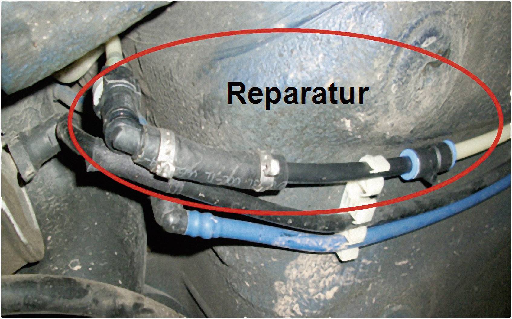 Close-up van auto-onderdelen met een slang die gemarkeerd is met een rode cirkel en het woord 'Reparatie'.