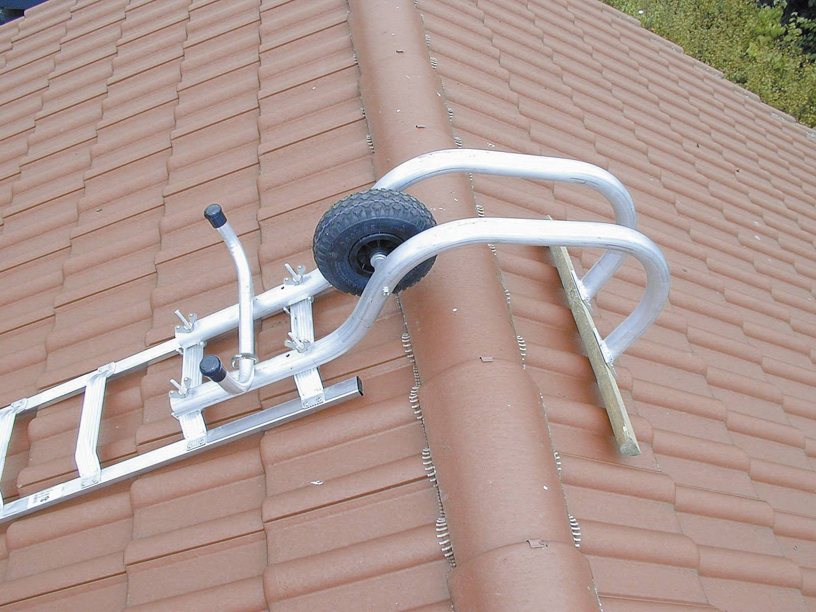 Een metalen ladder met een wiel ligt dwars over een pannendak. De ladder lijkt te worden gebruikt om hogere plekken op het dak te kunnen bereiken.