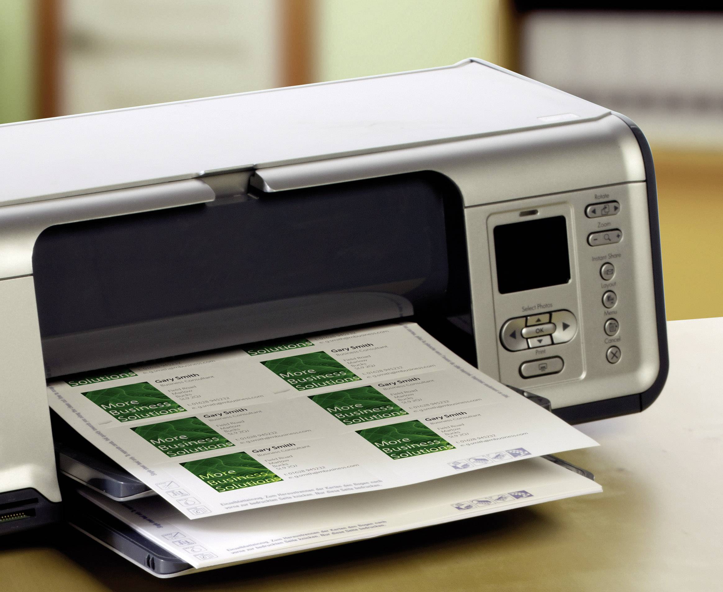 Een printer geeft bedrukte etikettenvellen uit. De printer staat op een tafel, op de achtergrond zijn onscherpe kantoormeubels te zien.