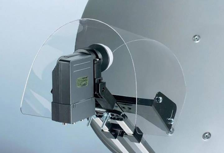 Een schotelantenne met een beschermkap op de LNB, gemonteerd op een metalen steun.