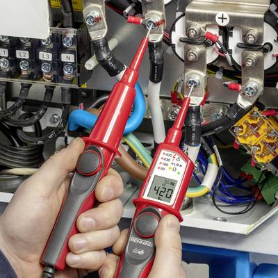 Osoba mierzy napięcie multimetrem w skrzynce elektrycznej. Multimetr wskazuje 420 woltów.