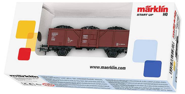 Wagonik węglowy modelu pociągu w białym pudełku z kolorowym wzorem i brandingiem "Märklin Start Up". Wyświetlona strona internetowa "www.maerklin.com".