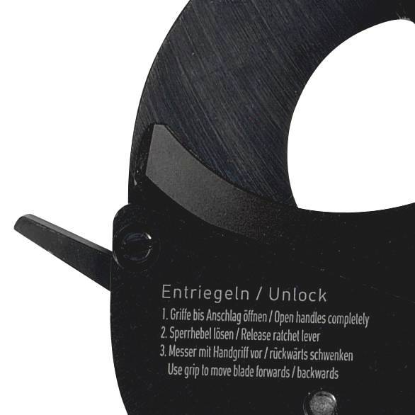 Mechanizm odblokowania narzędzia z instrukcjami w języku niemieckim i angielskim dotyczącymi odblokowania i kierunku użycia.