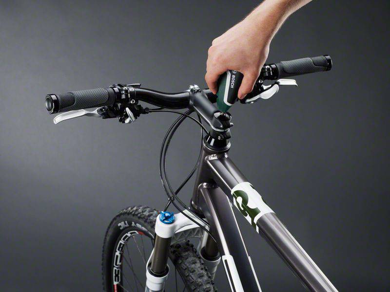 Dłoń pokazuje regulację kierownicy roweru górskiego za pomocą klucza imbusowego. Kierownica jest zamontowana na rowerze górskim.