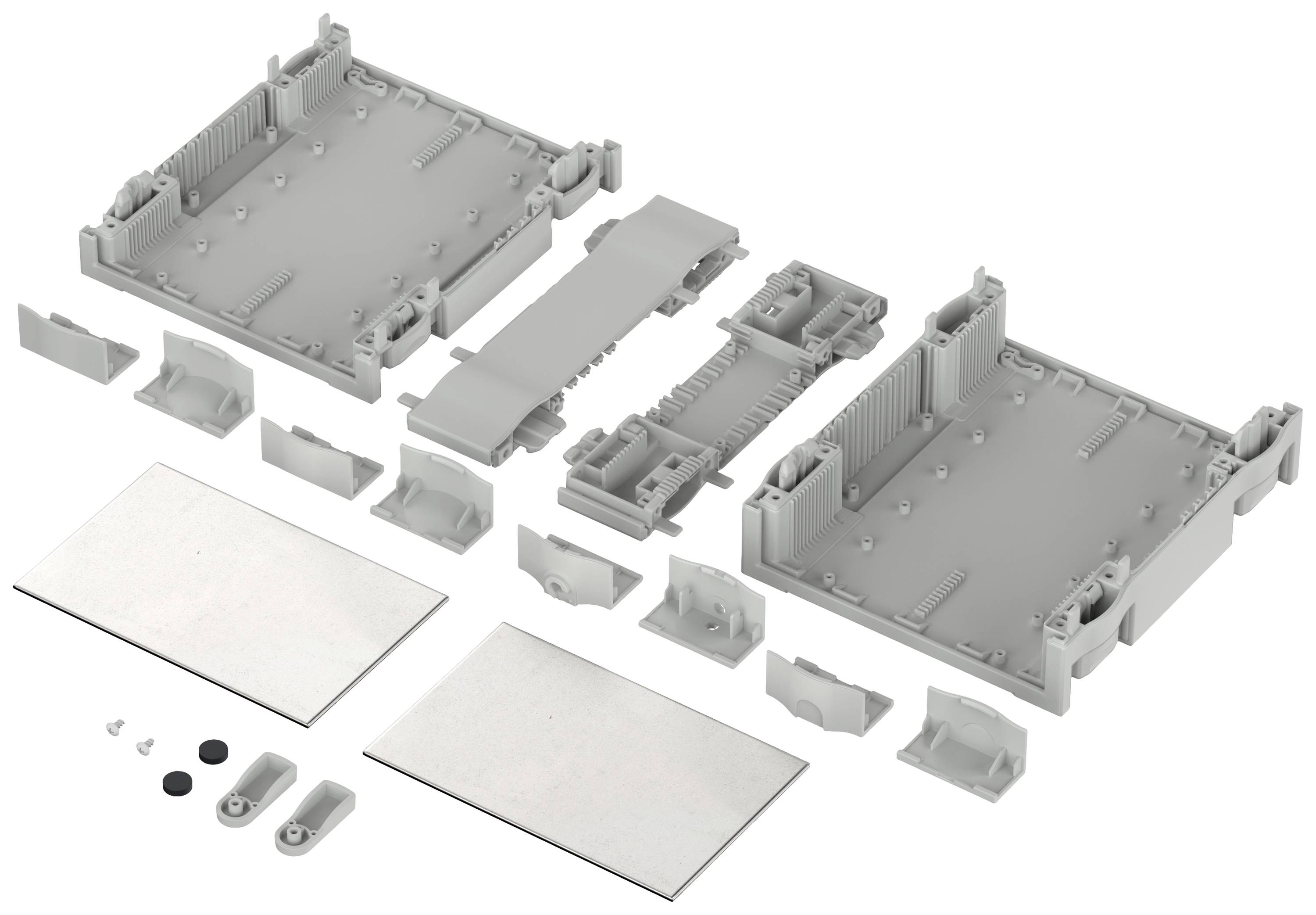 Szare obudowa elektroniczna, składająca się z kilku elementów, leży rozłożona na stole. Widoczne są różne elementy mocujące.