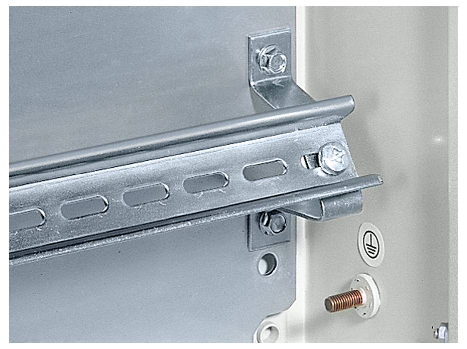 Kątownik montażowy z ocynkowanego profilu stalowego i śrub; obok symbol uziemienia oraz miedziana śruba zamocowana na ścianie.