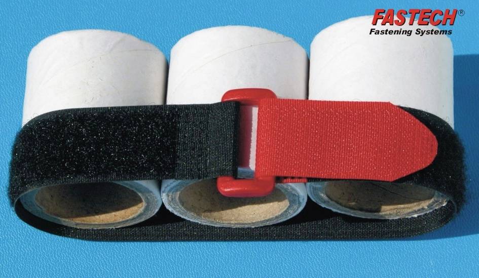 Trzy rolki papieru owinięte taśmą rzepową, czerwona zakładka na górze. Nazwa marki 'FASTECH Fastening Systems' w prawym górnym rogu.