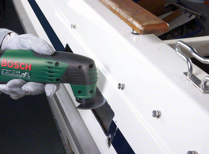 Osoba szlifuje powierzchnię łodzi zielonym elektronarzędziem. Po lewej stronie widoczne jest logo Bosch na urządzeniu.