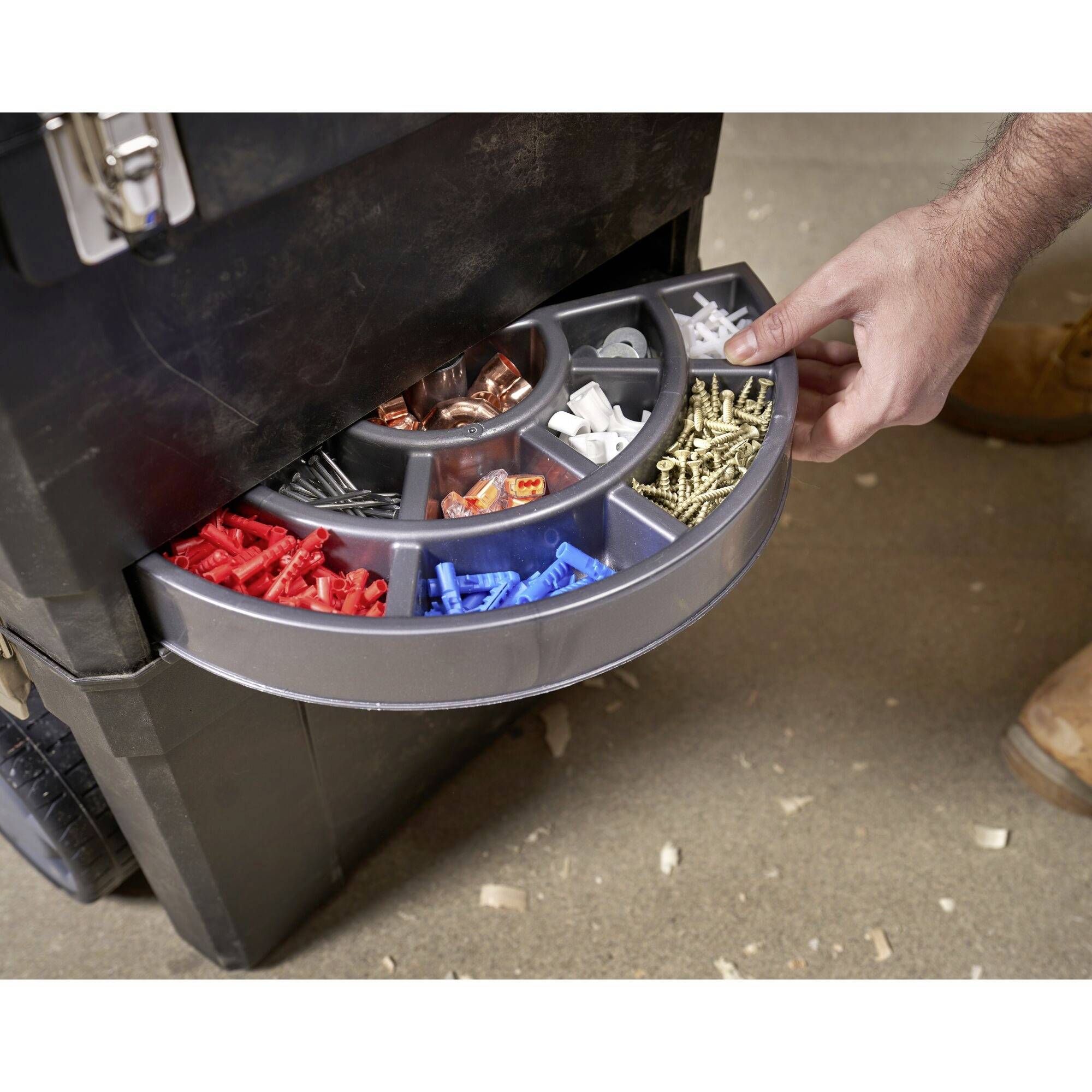 Ręka wyciąga szufladę z posortowanymi śrubami i kołkami w różnych kolorach i rozmiarach z pudełka na narzędzia.