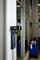 Czarna stacja ładowania do elektronarzędzi jest zamocowana na ścianie. Na tylnym planie znajduje się wózek warsztatowy z różnymi narzędziami.