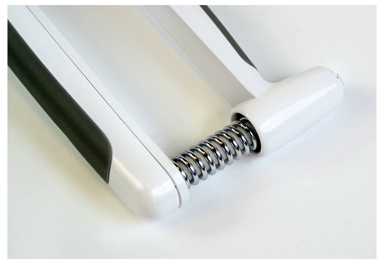 Biały i czarny ręczny trener mięśni z mechanizmem sprężynowym leży na jasnej powierzchni.