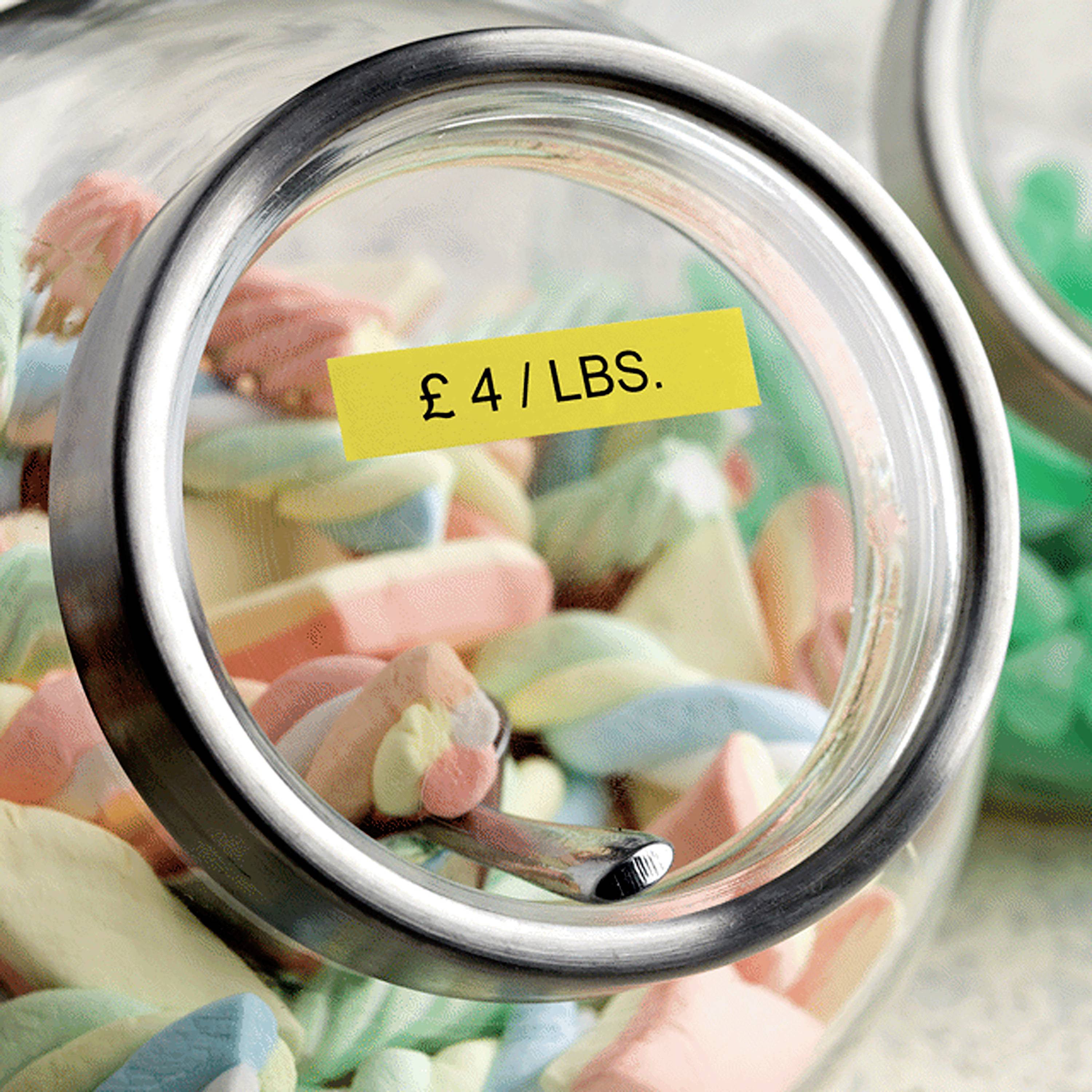 Słoik z różnokolorowymi cukierkami i żółtą etykietą cenową '£ 4 / LBS.'