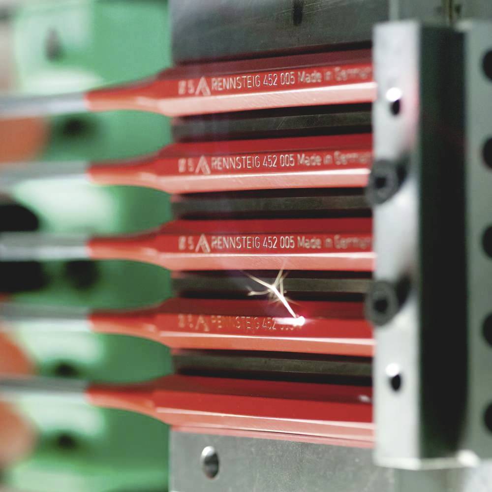 Iskra przeskakuje z czerwonego narzędzia umieszczonego w metalowym uchwycie. Na narzędziu widnieje napis „Made in Germany".