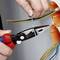 Osoba ucina kabel za pomocą szczypiec do ściągania izolacji. Kabel posiada kilka kolorowych żył i jest instalowany w puszce ściennej.
