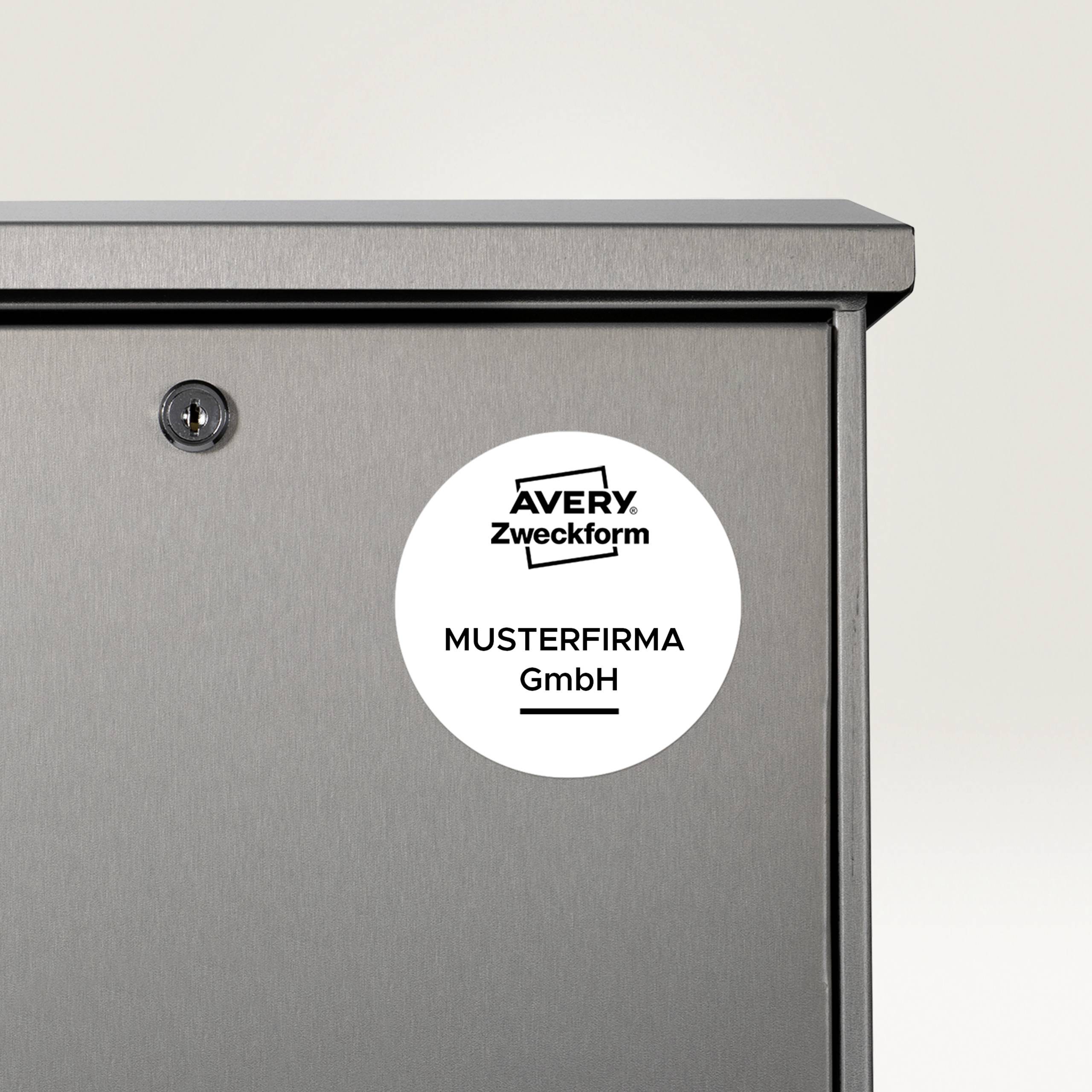 Srebrna skrzynka pocztowa z okrągłą naklejką z napisem 'Musterfirma GmbH'.