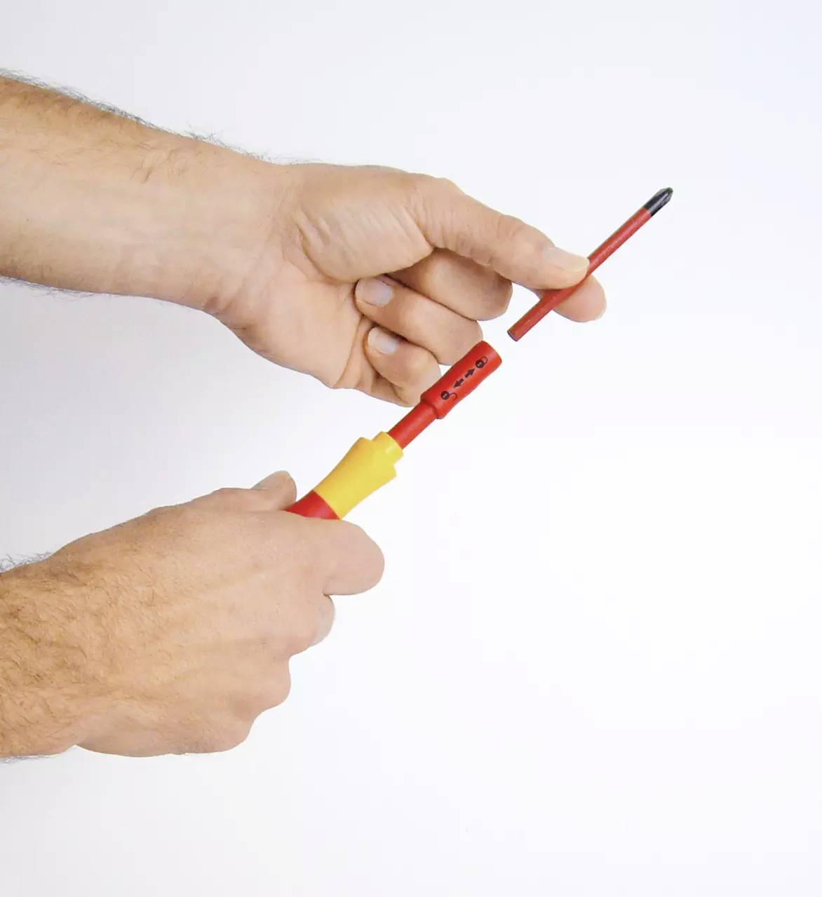 Dwie ręce trzymają izolowany śrubokręt w kolorach czerwono-żółtych, przy czym ostrze jest wyjmowane lub wkładane.