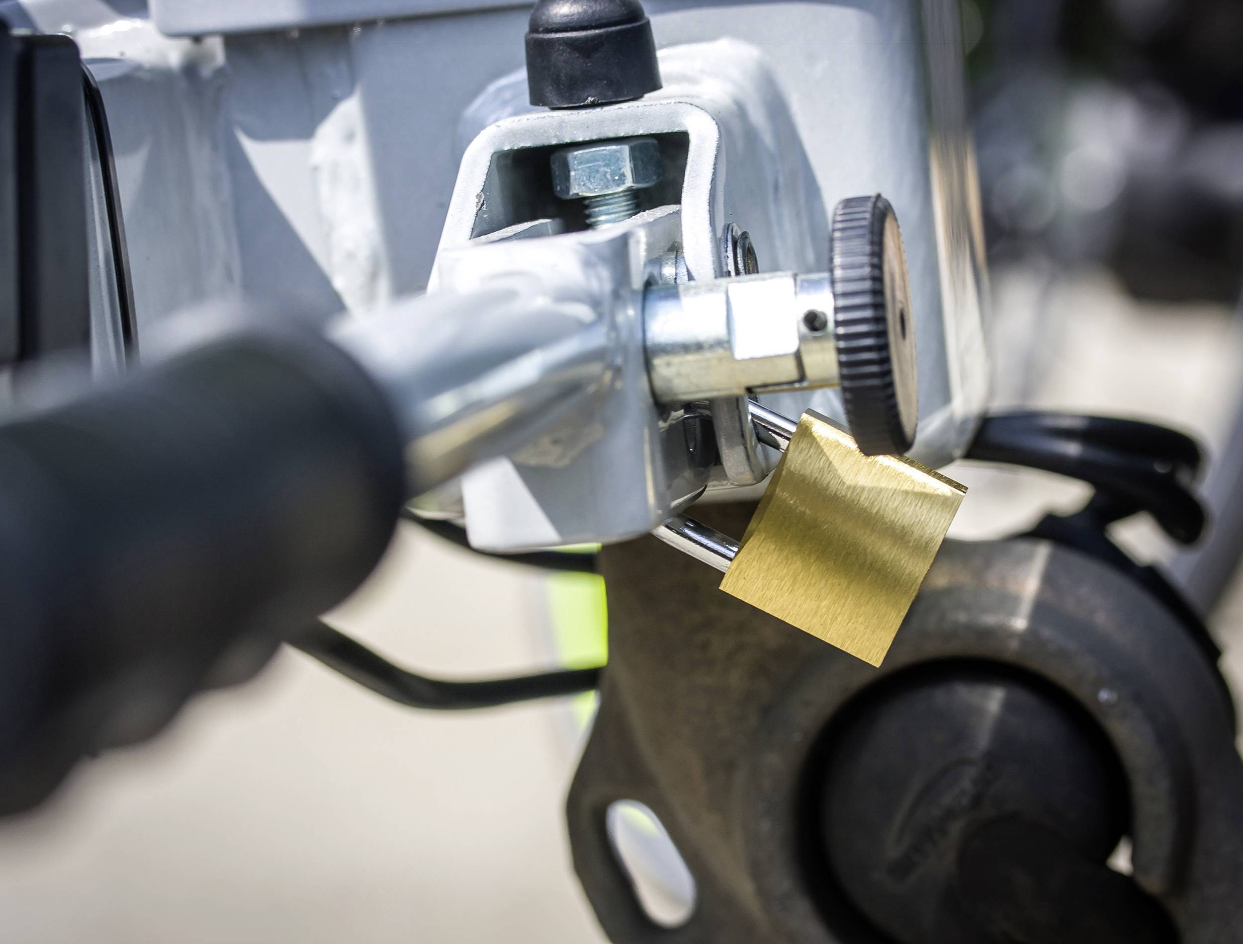 Zbliżenie kłódki roweru przypiętej do ramy. Kłódka jest mała, w kolorze złotym.