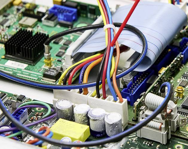 Zbliżenie płyty głównej z różnymi kablami, złączami i elementami elektronicznymi.