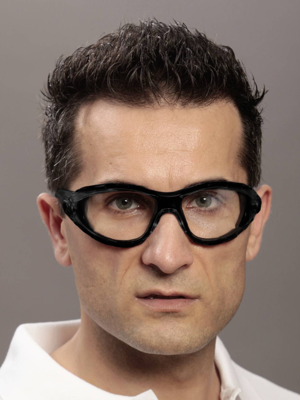 Osoba o krótkich ciemnych włosach nosi okulary ochronne. Tło jest neutralnie szare.
