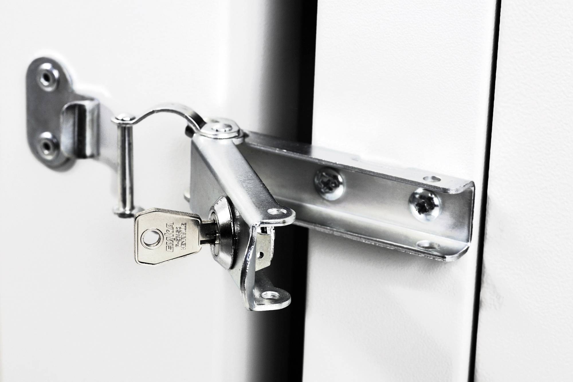 Drzwi z metalowym zawiasem, zamkiem zabezpieczającym i kluczem, podkreślające koncentrację na bezpieczeństwie lub kontroli dostępu.