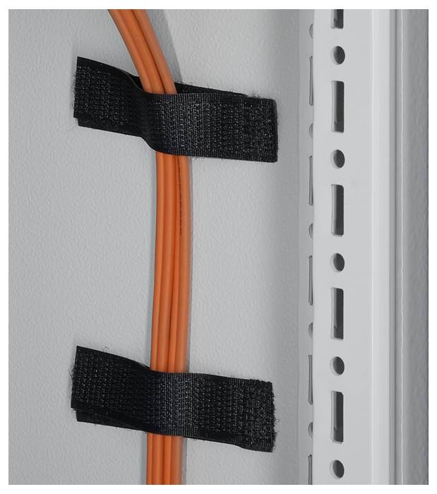 Pomarańczowy kabel jest przymocowany do jasnoszarej ściany za pomocą dwóch czarnych opasek rzepowych, obok perforowanej szyny metalowej.