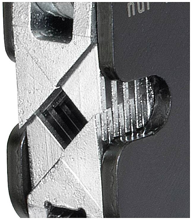 Zbliżenie kawałka metalu o ząbkowanych krawędziach i gładkim, błyszczącym obszarze po prawej stronie. Potencjalne zastosowanie przemysłowe.