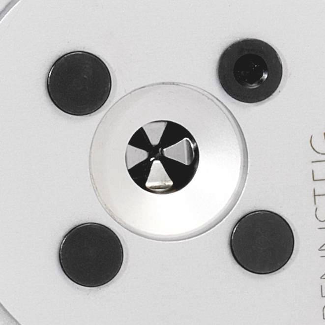 Zbliżenie okrągłego przedmiotu metalowego z czarnym wzorem punktowym i centralnym gniazdem śrubowym. Funkcja nieznana.