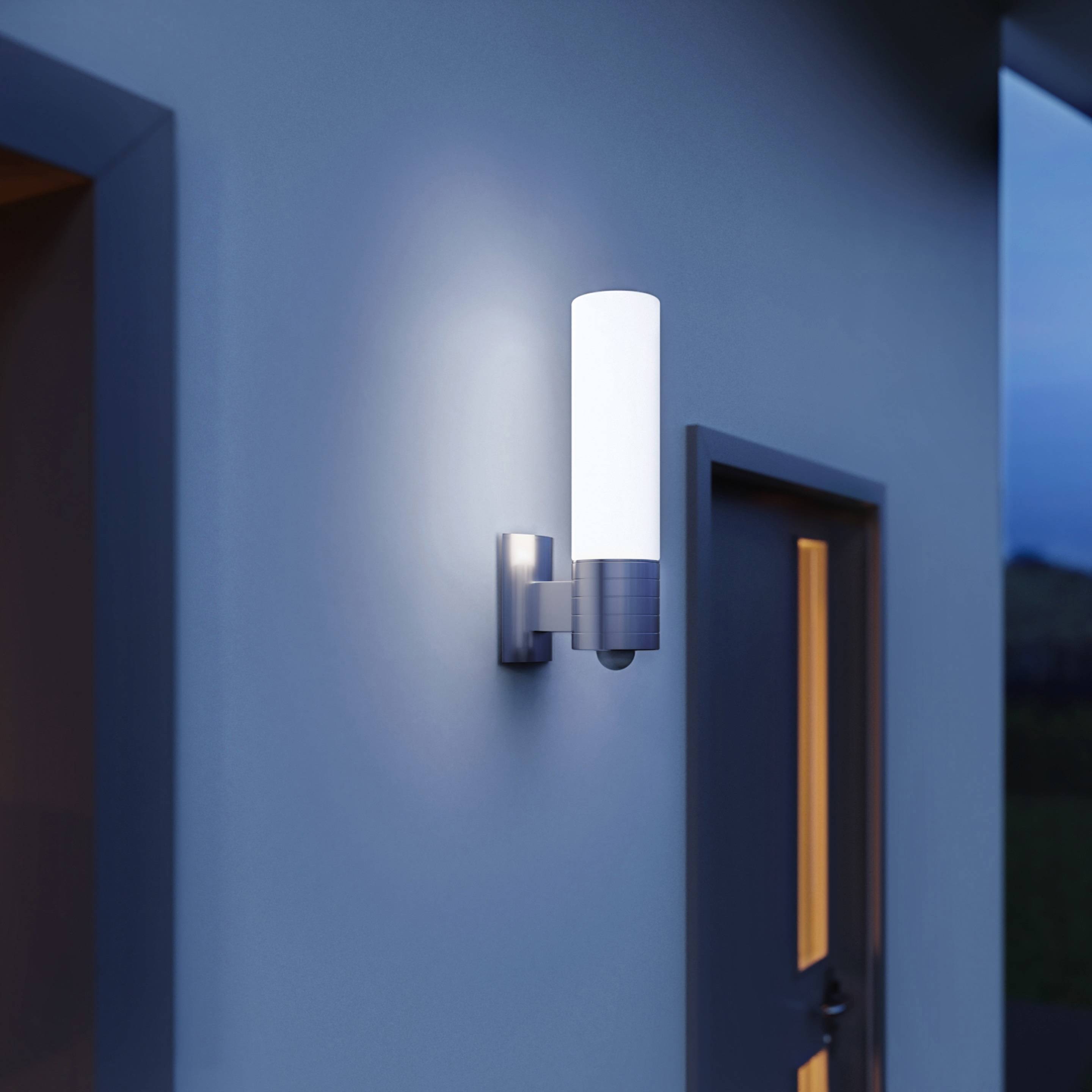 Lampa zewnętrzna o nowoczesnym designie zamocowana na ścianie domu, świecąca o zmierzchu, zapewniająca lepszą widoczność i bezpieczeństwo.