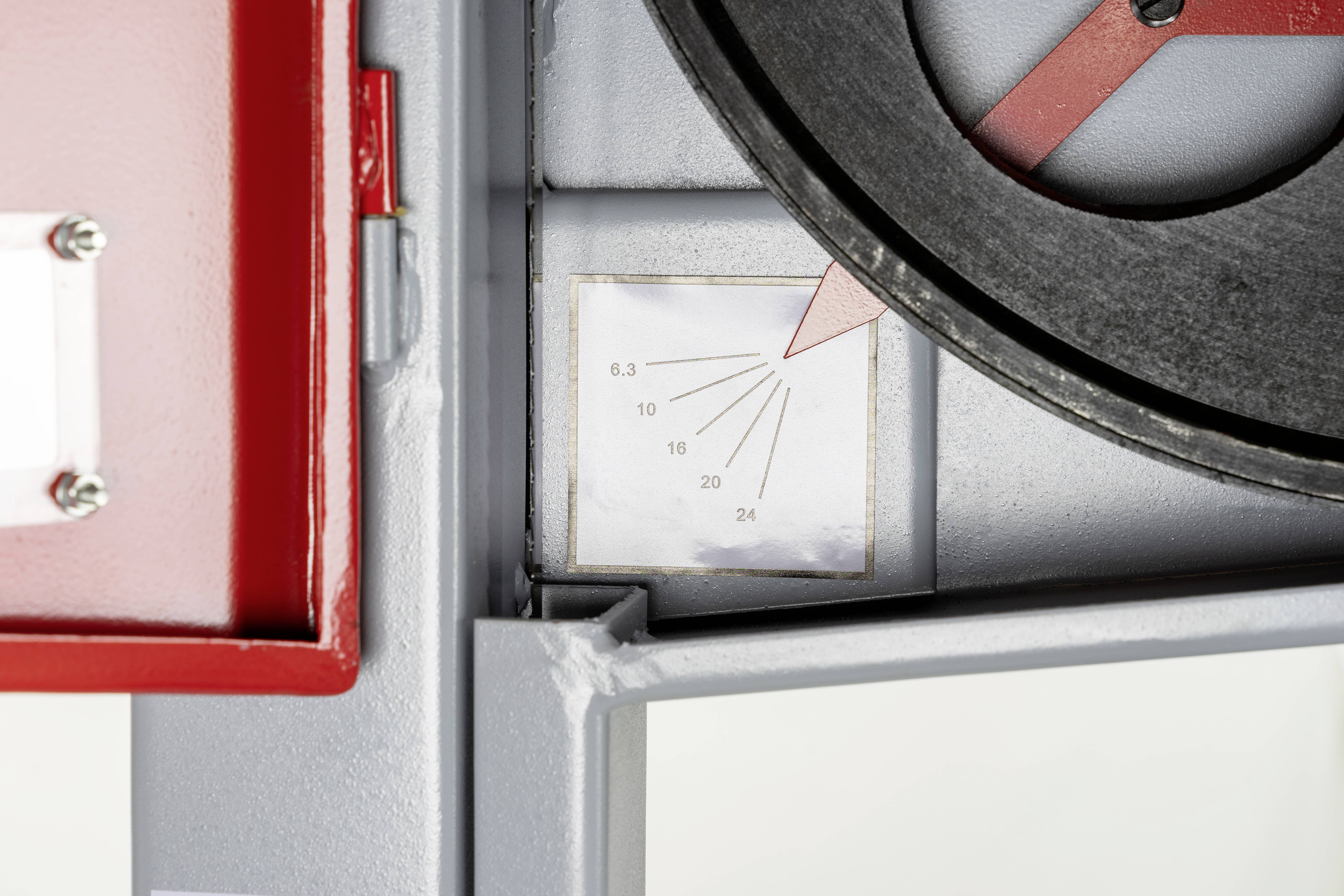 Metalowe urządzenie ze skalą od 8,3 do 24. Wskazówka pomiarowa wskazuje na skalę. W lewym górnym rogu widoczna czerwona obudowa.