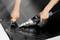 Dwie ręce używają narzędzia do spawania czarnego materiału przez przyłożenie ciepła; ujęcie szczegółowe procesu.