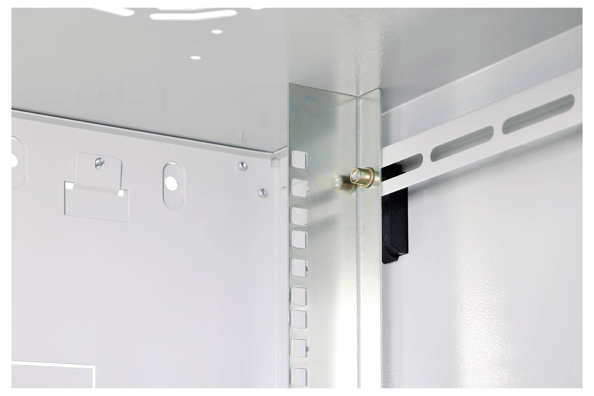 Obraz przedstawia wewnętrzny narożnik metalowej obudowy elektrycznej, z zamontowaną szyną montażową ze szczelina oraz śrubą narożną mocującą komponenty.