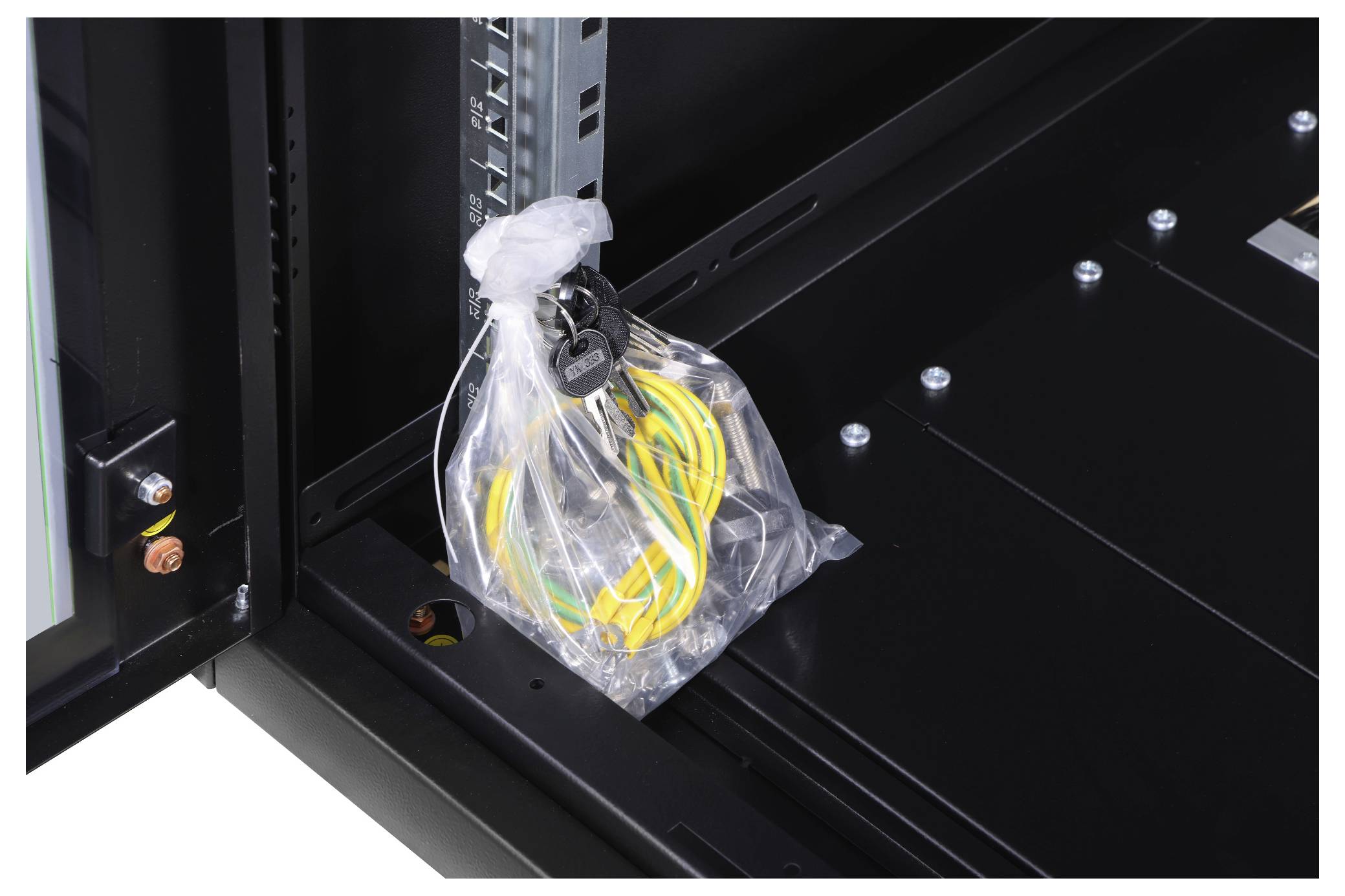 Torba plastikowa z żółtymi i zielonymi kablami oraz pękiem kluczy w czarnej metalowej szafce.
