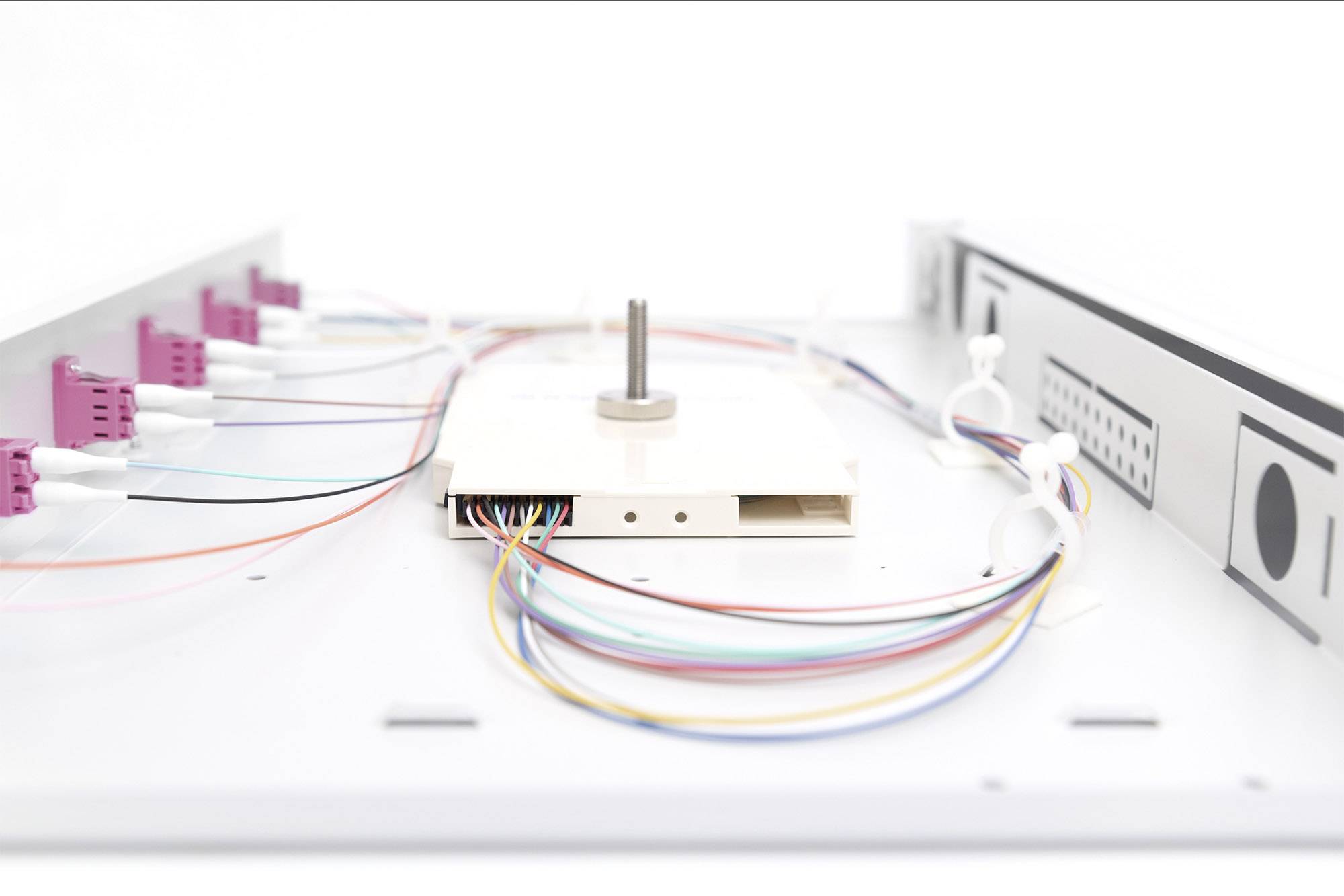 Urządzenie techniczne w białej obudowie z kolorowymi kablami i złączami, prawdopodobnie przeznaczone do przesyłania danych lub energii elektrycznej.