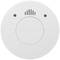 Okrągły czujnik dymu w kolorze białym z napisem 'TEST/HUSH'. Widoczne są dwa otwory na wkręty oraz otwory wentylacyjne.