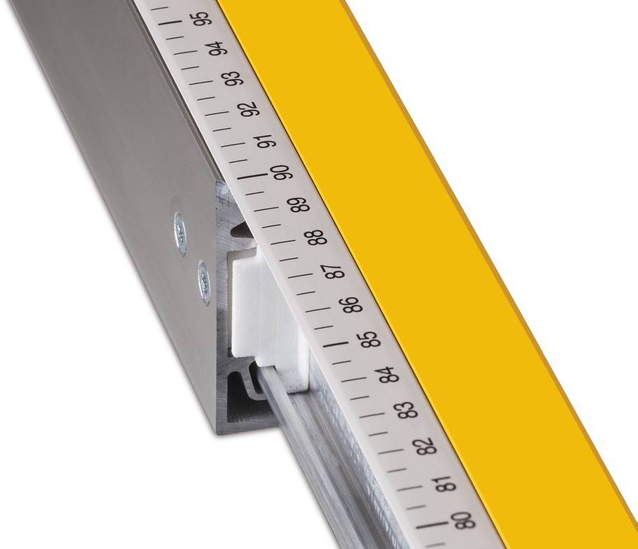 Zbliżenie taśmy mierniczej na żółtym linijce z metalowym uchwytem; widoczne liczby od 60 do 90.