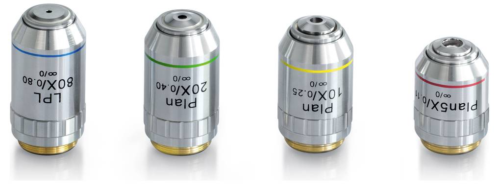 Cztery obiektywy mikroskopowe o różnych rozmiarach z kolorowymi oznaczeniami: niebieski (80X/0,80), zielony (20X/0,40), żółty (10X/0,25), czerwony (4X/0,10).