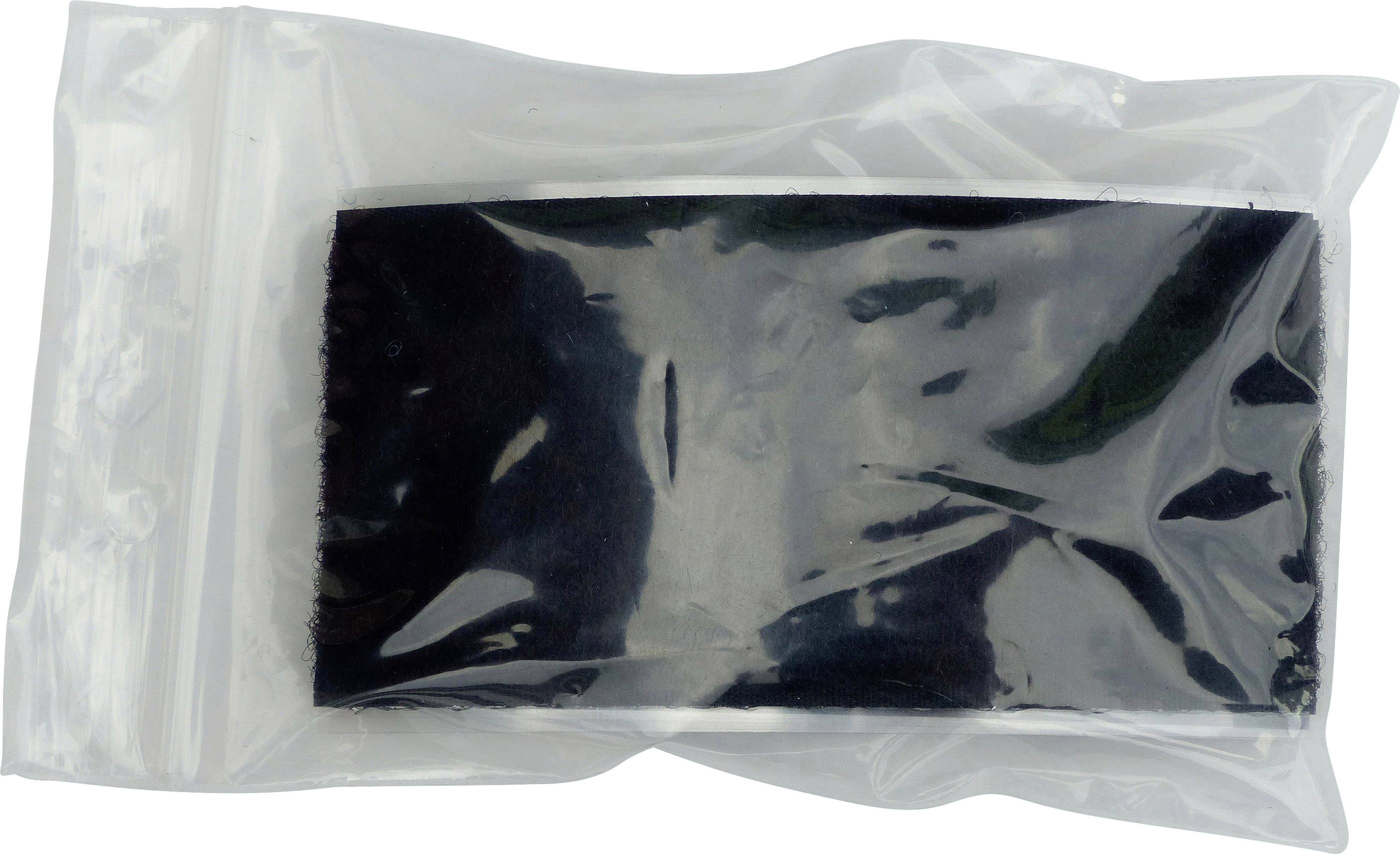 Czarny obiekt w przezroczystej torbie plastikowej, prawdopodobnie urządzenie elektroniczne lub akcesoria, na białym tle.