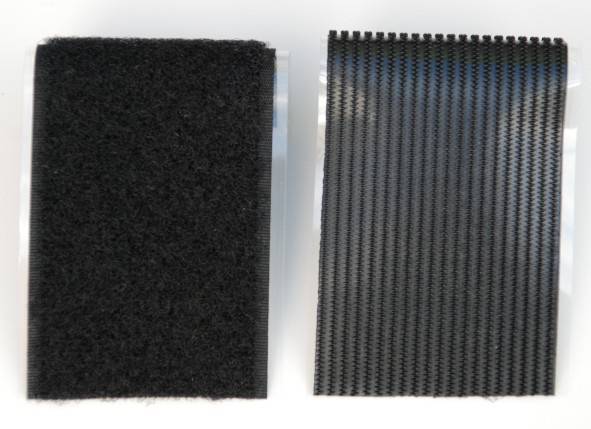 Dwa czarne paski rzepowe ułożone obok siebie, po lewej stronie miękkie i puszyste, po prawej stronie z strukturą haczyków, na jasnym tle.