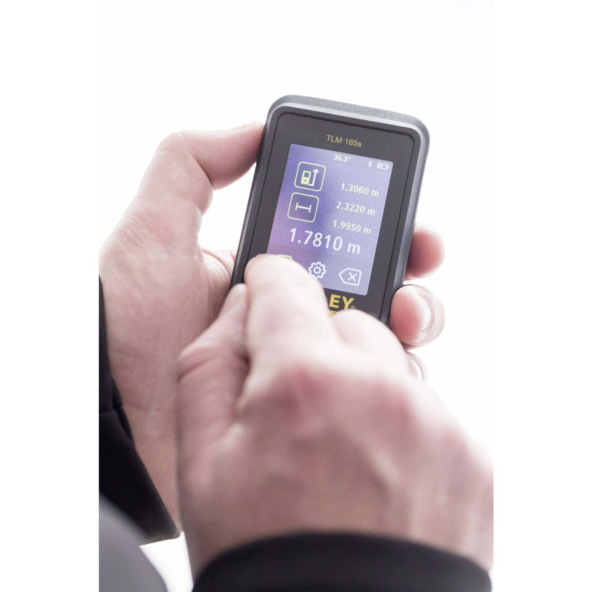 Osoba obsługuje przenośne cyfrowe urządzenie pomiarowe z wyświetlaczem pokazującym pomiary w metrach.
